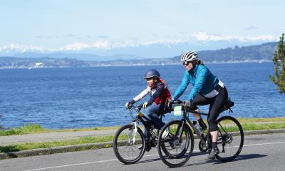 An adult and teen ride past the stunning Puget Sound on the 2025 Ride for Major Taylor