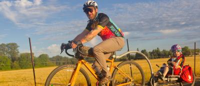 A rider and and a child pedal past beautiful yellow fields on STP in 2025.