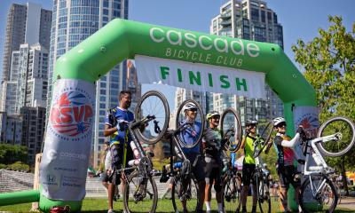 A group of riders celebrate at the Vancouver, BC finish line in 2025.