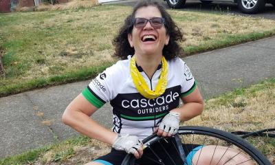 Outrider smiling and changing a tube on the sidewalk