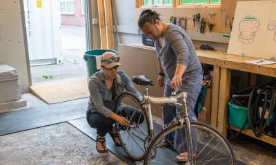 An instructor demonstrates how to remove the back tire for a student during a Basic Bike Maintenance Class