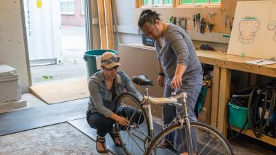 An instructor demonstrates how to remove the back tire for a student during a Basic Bike Maintenance Class