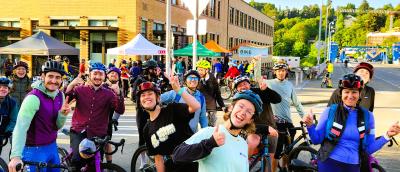 A group of cyclists smiling in front of the Fremont Bridge
