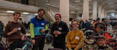 A group of vendors sits or stands behind a table of good and smiles at the camera.