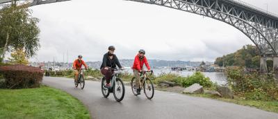 Three people bike on the Burke-Gilman Trail.
