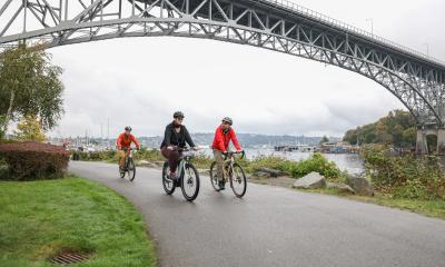Three people bike on the Burke-Gilman Trail.