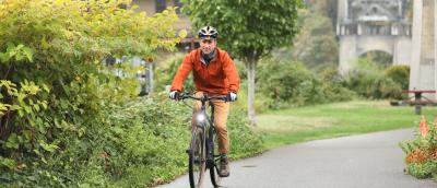 A man in a orange jacket biking on the Burke-Gilman Trail in Fremont.