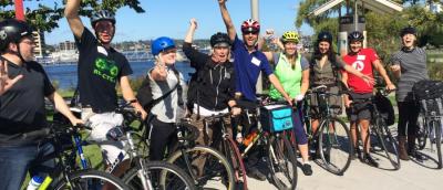 Group of enthusiastic volunteers on their bikes with their arms in the air