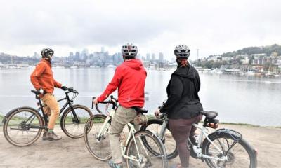 Three bicyclists looking out over the water towards the city skyline, pondering the future of our world in the face of climate change.