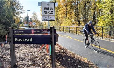 Single bike rider on a protect bike trail. The trees in the background are changing their colors giving early signs of fall in the Pacific Northwest