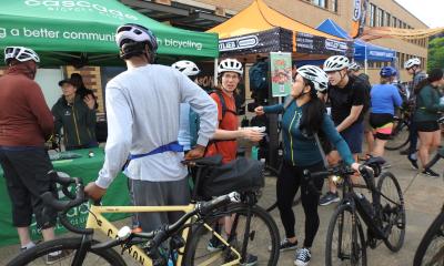 Riders gather in front of a line of tents at a celebration station.
