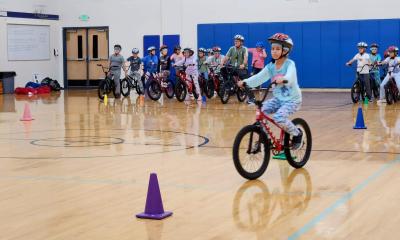 Child riding a bike in a gym as part of the Let's Go program
