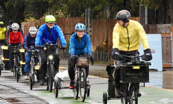 Five cyclists pulling trailers of food