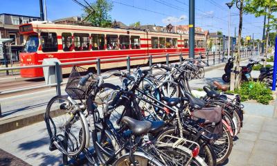 A line of parked Dutch bikes near a tram in the Hague region by Melissa and Chris Bruntlett