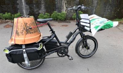 A Tern e-bike carries a flower pot and a bag of soil. 