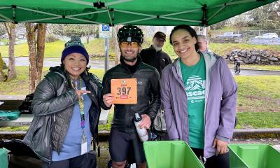Two volunteers giving a rider bib to a cyclist