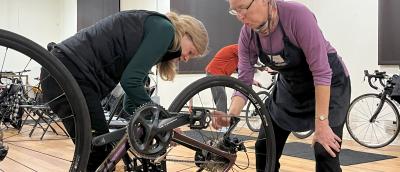 An instructor and a student looking at a bike wheel