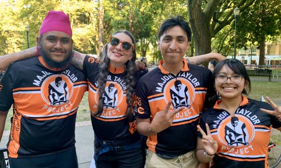MTP students and staff at the Portland finish line of the Seattle to Portland ride in 2024, wearing their orange and black MTP jerseys