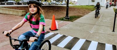 A young girl bikes past a crosswalk during a Let's Go in-school bike education class