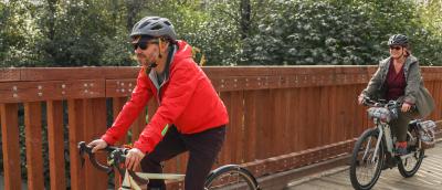 Two people ride bicycles on a flat trail