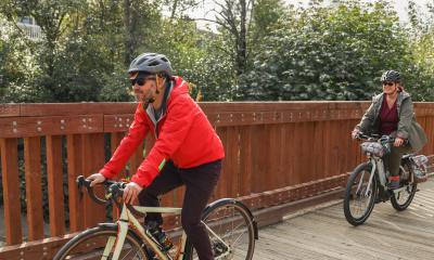 Two people ride bicycles on a flat trail