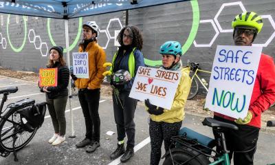 Advocates hold signs that read "Safe Streets Now"