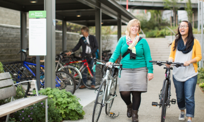 Two cyclists walking their bikes on the sidewalk