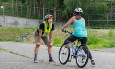 An instructor teaches someone how to ride a bike