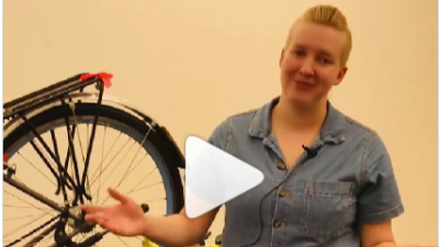 A woman stands next to a bike and gives tips on wet weather riding. 
